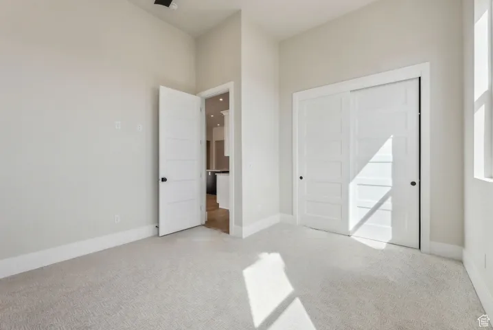 Unfurnished bedroom with light colored carpet and baseboards