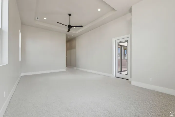 Carpeted spare room with baseboards, ceiling fan, a tray ceiling, and recessed lighting