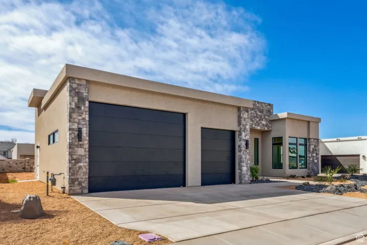 Contemporary house with an attached garage, stucco siding, driveway, and stone siding