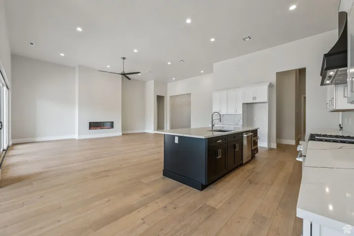 Kitchen featuring white cabinets, ceiling fan, a sink, light wood-style floors, and light countertops