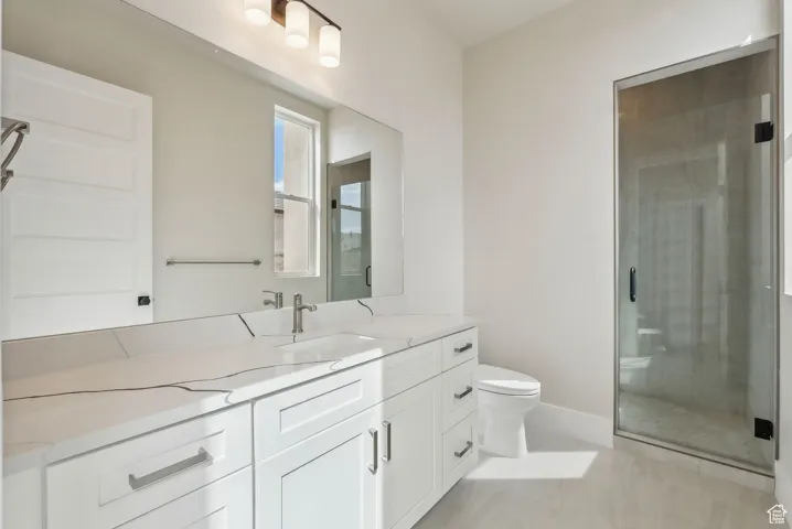 Bathroom featuring vanity, baseboards, a stall shower, and toilet