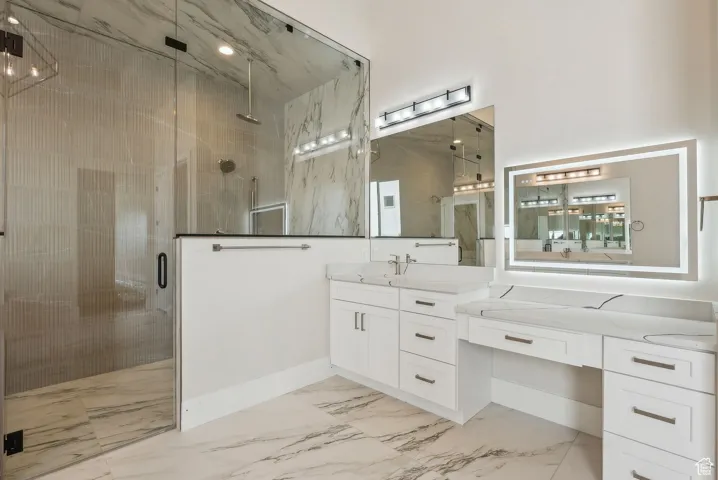 Full bathroom featuring vanity, baseboards, a shower stall, and marble finish floor