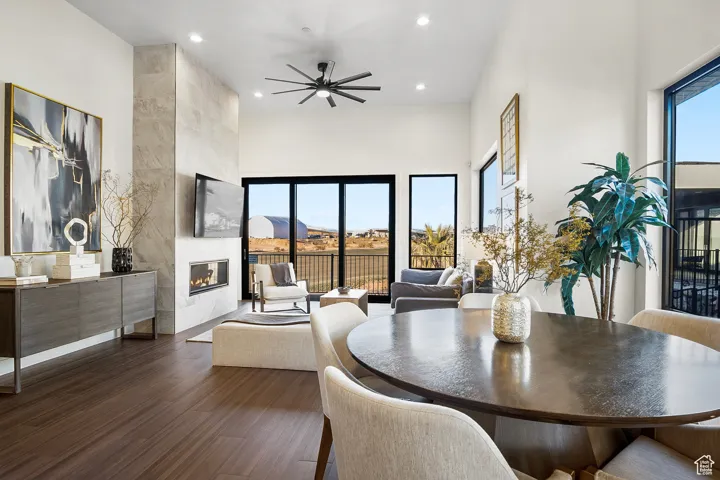 Dining space featuring dark hardwood / wood-style floors, ceiling fan, a tile fireplace, and a towering ceiling