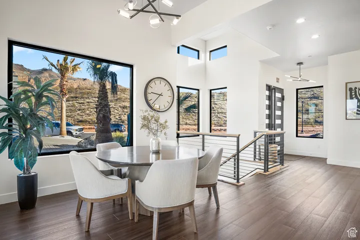 Dining area featuring plenty of natural light, dark hardwood / wood-style flooring, a towering ceiling, and a notable chandelier