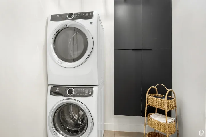 Washroom with stacked washer / dryer and tile floors