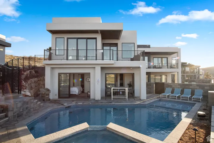 Back of property with a patio, a pool with hot tub, and a balcony