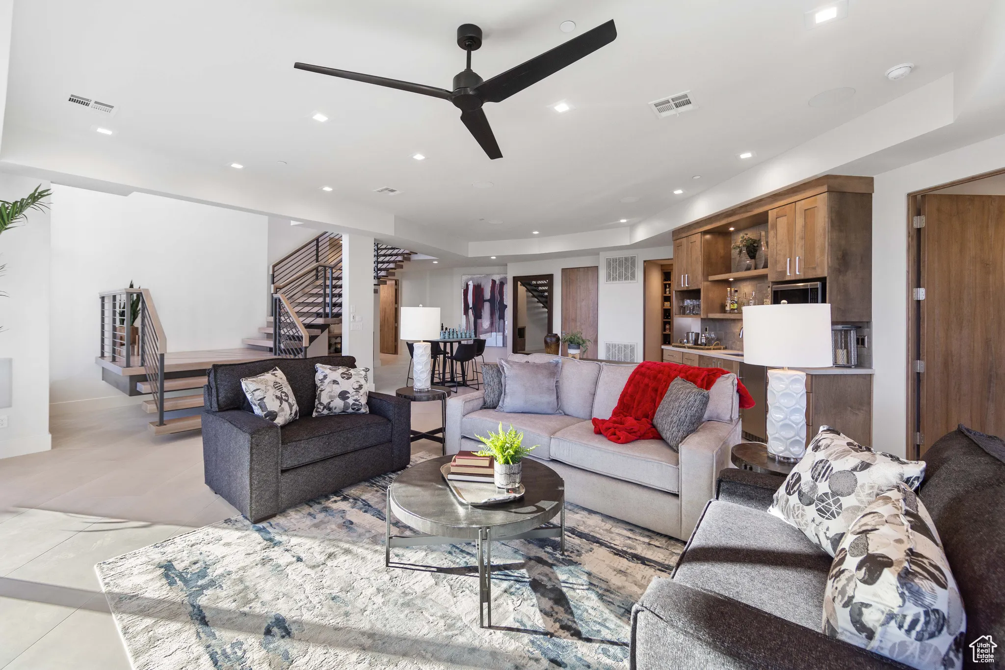 Tiled living room featuring ceiling fan and a tray ceiling