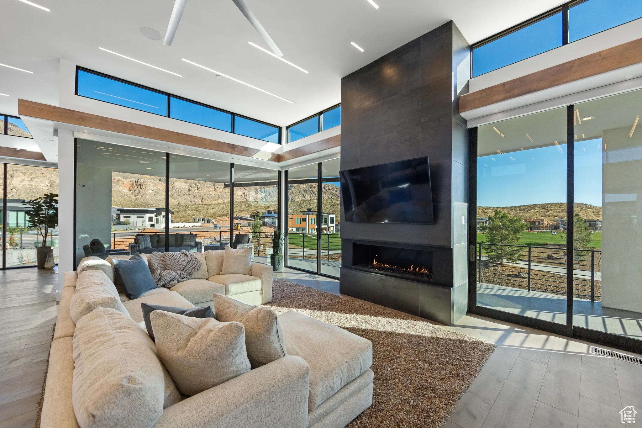 Living room featuring expansive windows, a healthy amount of sunlight, light wood-type flooring, and a fireplace