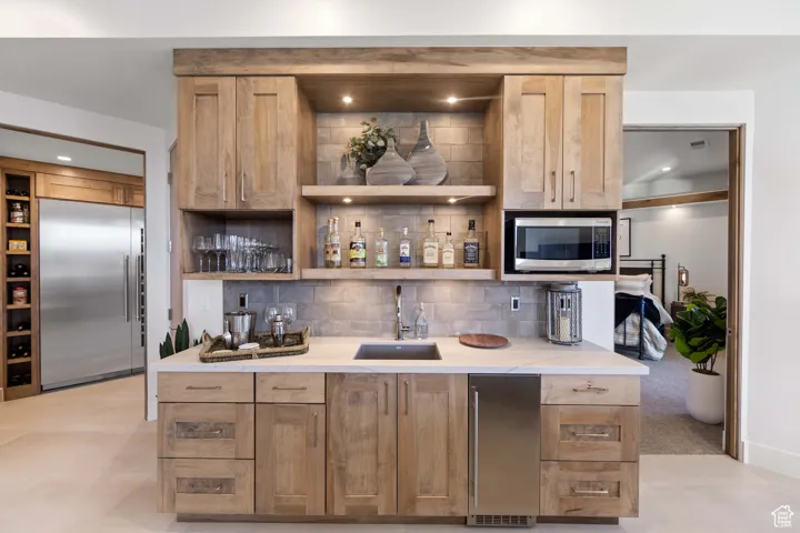 Kitchen with built in appliances, sink, tasteful backsplash, and light tile floors