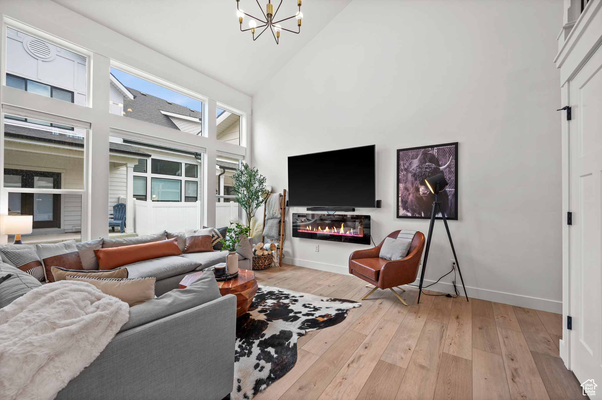 Living room with high vaulted ceiling, a notable chandelier, and light wood-type flooring