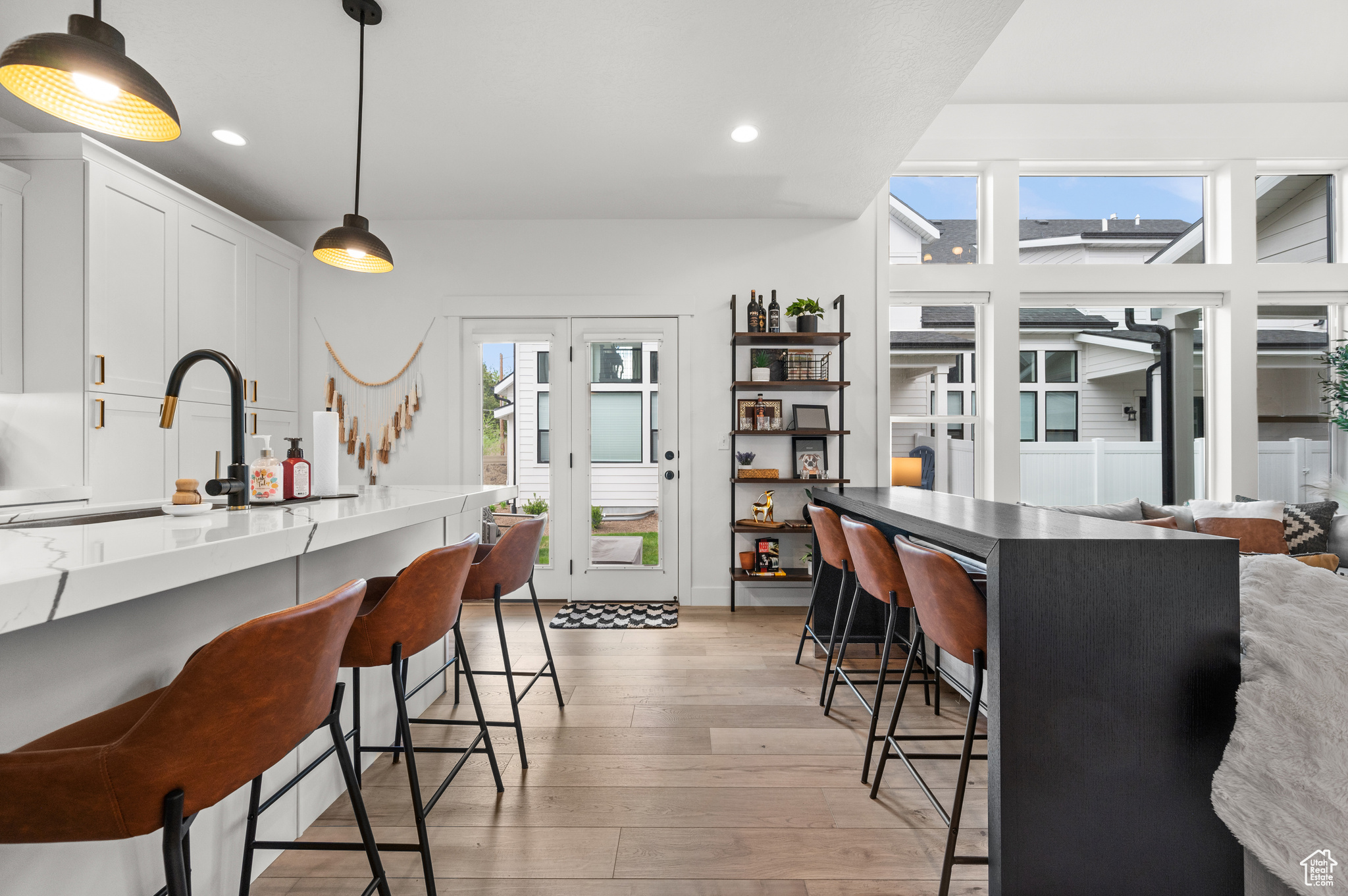 Kitchen with light hardwood / wood-style floors, pendant lighting, white cabinets, sink, and a kitchen bar