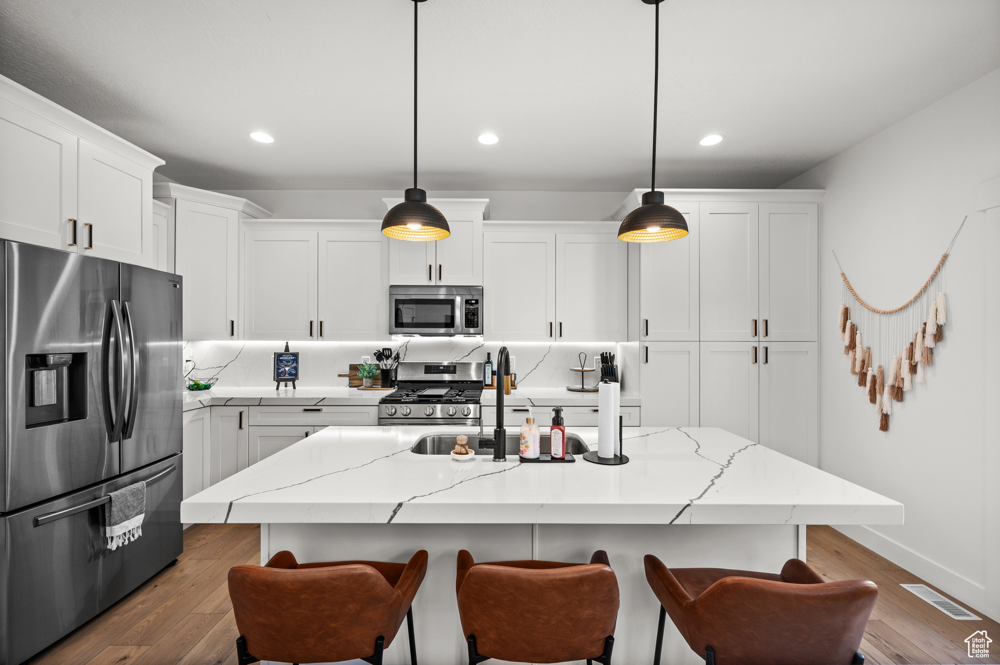 Kitchen with dark hardwood / wood-style floors, a center island with sink, stainless steel appliances, and white cabinets