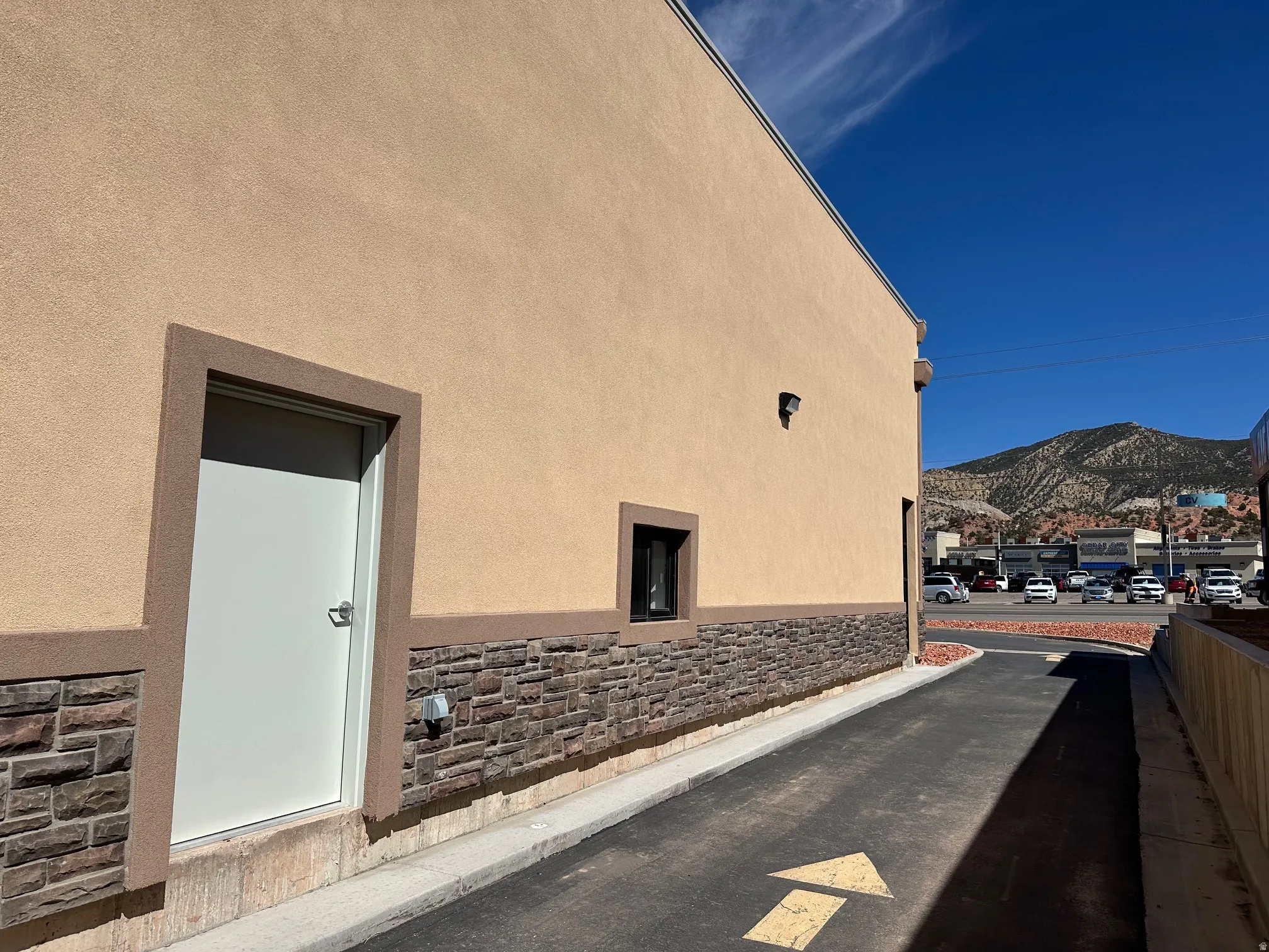 View of side of home featuring a mountain view, stone siding, and stucco siding