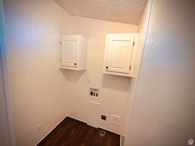 Washroom featuring cabinets, washer hookup, a textured ceiling, dark wood-type flooring, and hookup for an electric dryer