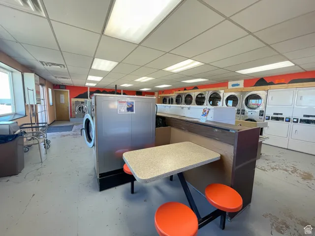 Interior space featuring white cabinetry, stacked washer and dryer, a kitchen bar, and a drop ceiling