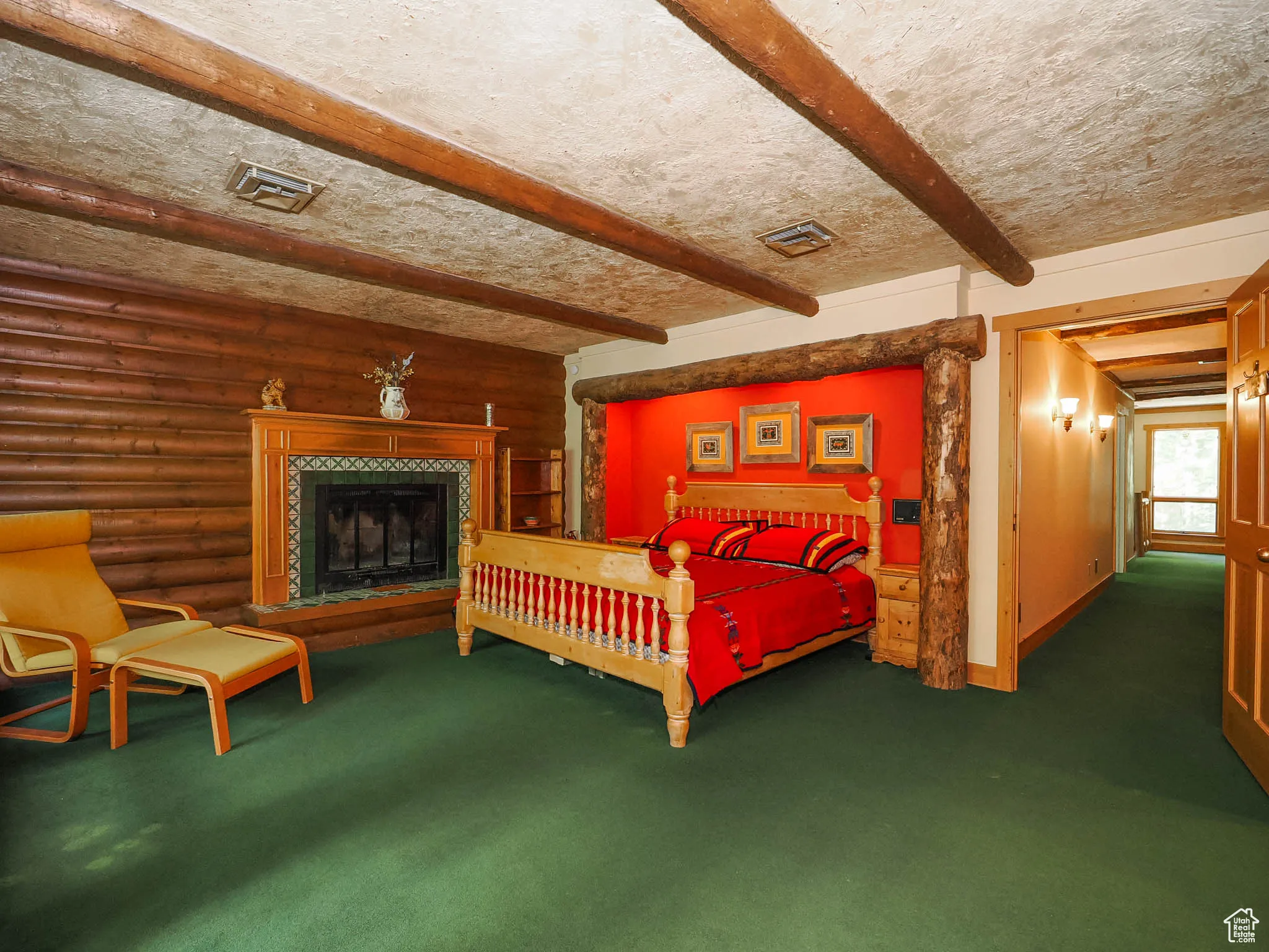 Primary suite on second floor with built-in bed alcove, log and beam accents, and private fireplace