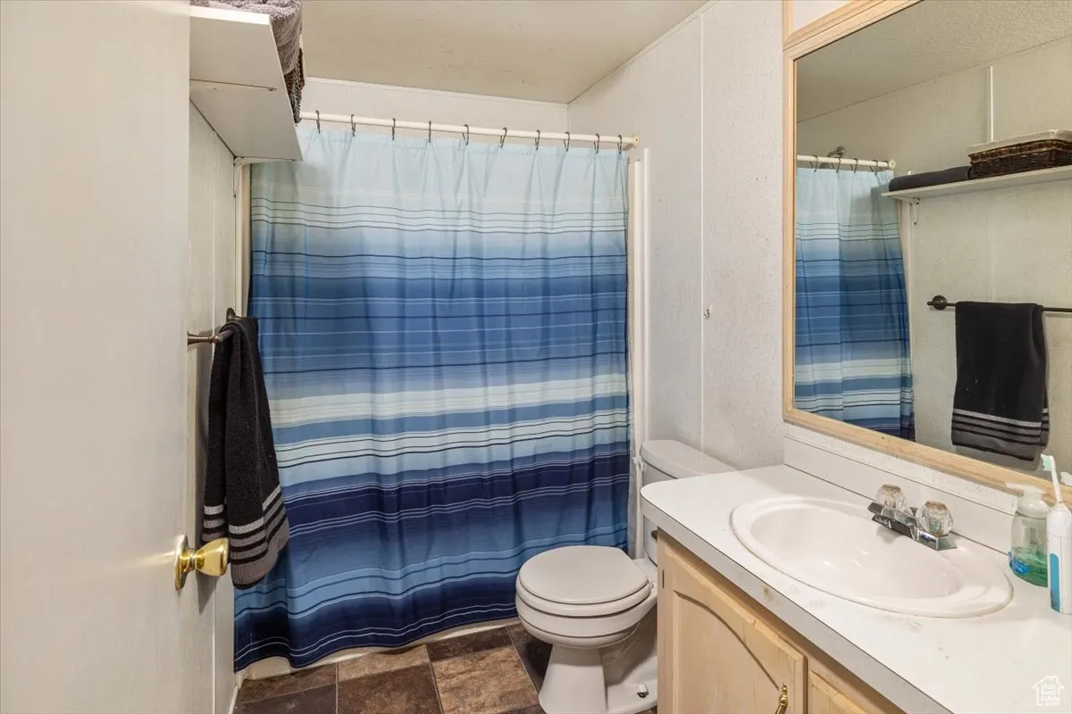 Unit A: Bathroom 2 featuring tile flooring, toilet, and large vanity