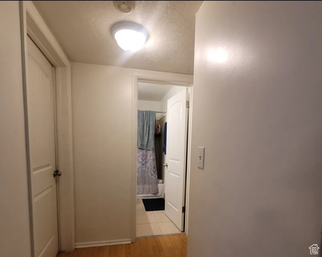 Hall with light tile patterned flooring and a textured ceiling