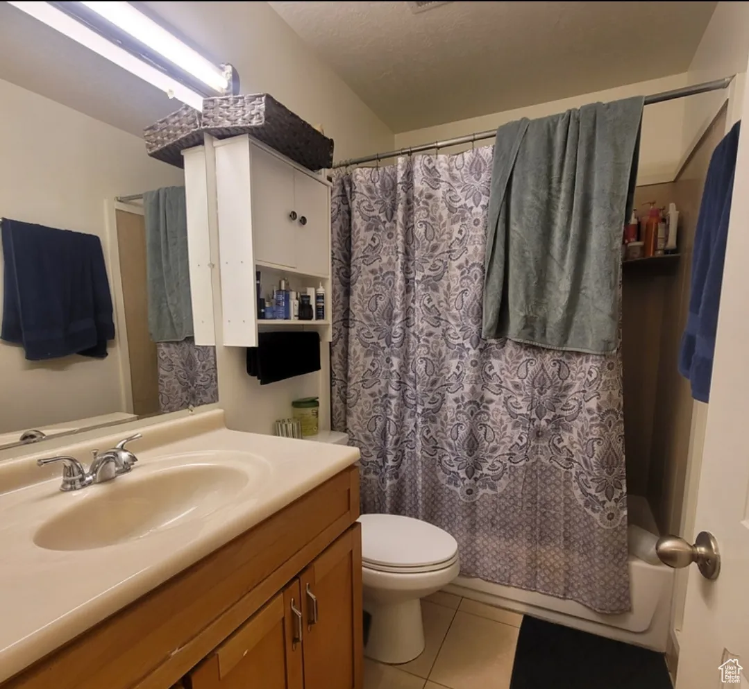 Full bathroom with shower / tub combo with curtain, vanity, tile patterned flooring, and toilet