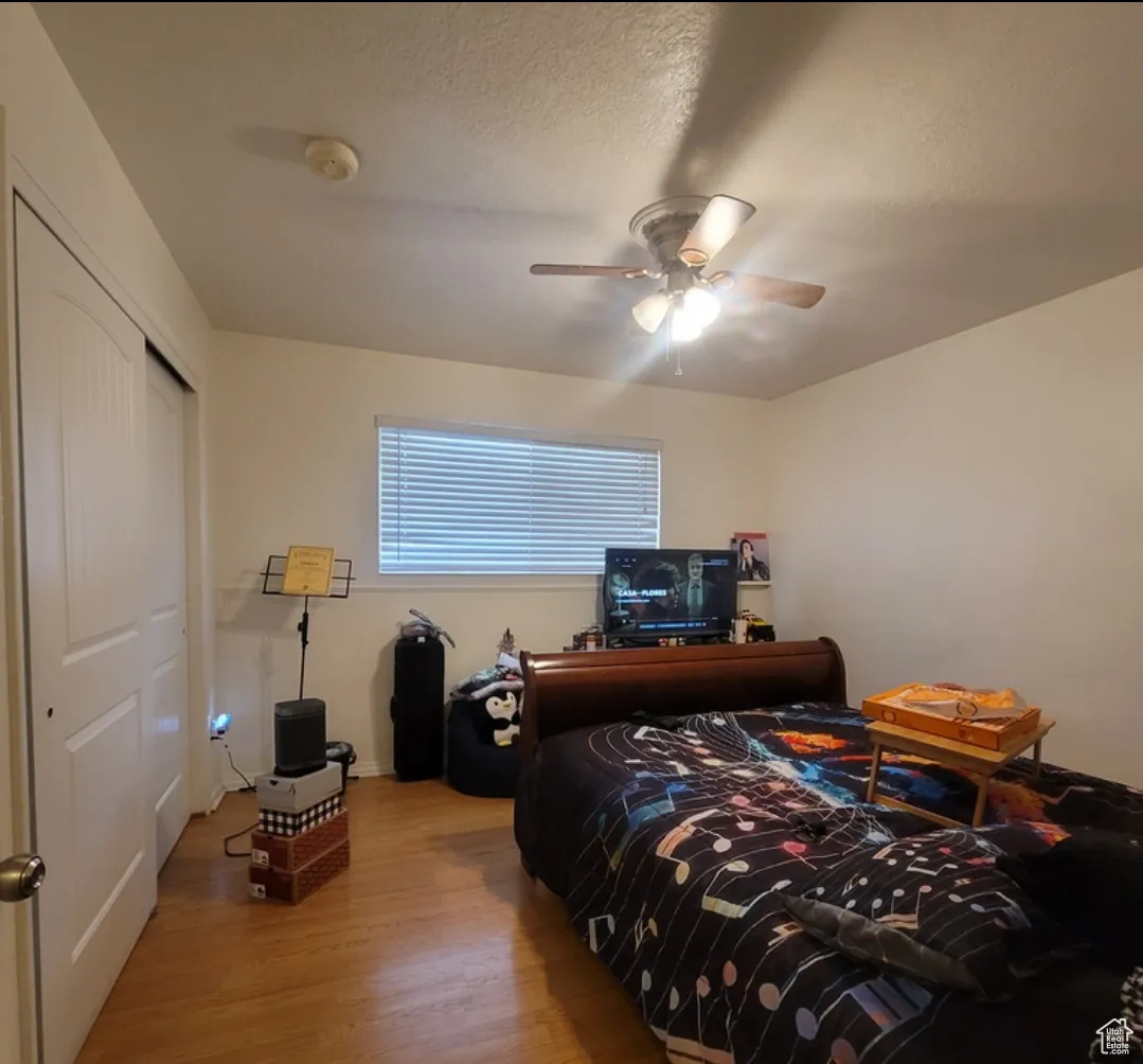 Bedroom with wood-type flooring, a textured ceiling, a closet, and ceiling fan