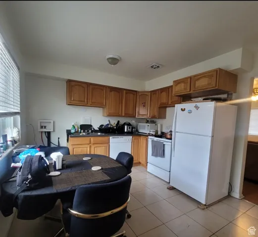 Kitchen with light tile patterned flooring and white appliances