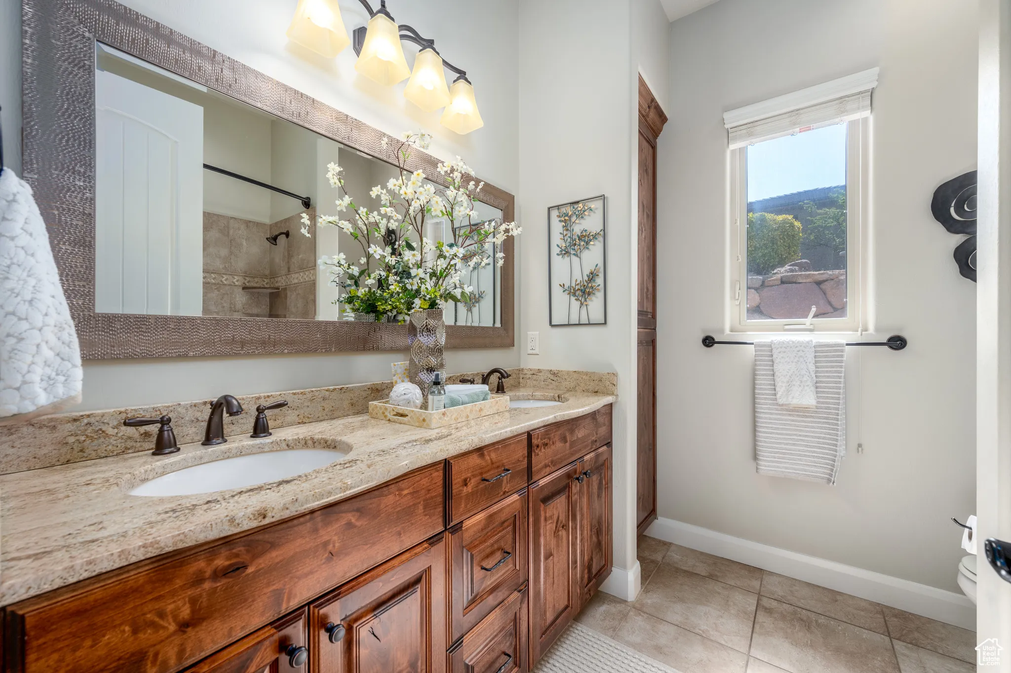Bathroom featuring tile patterned flooring, dual vanity, and tiled shower