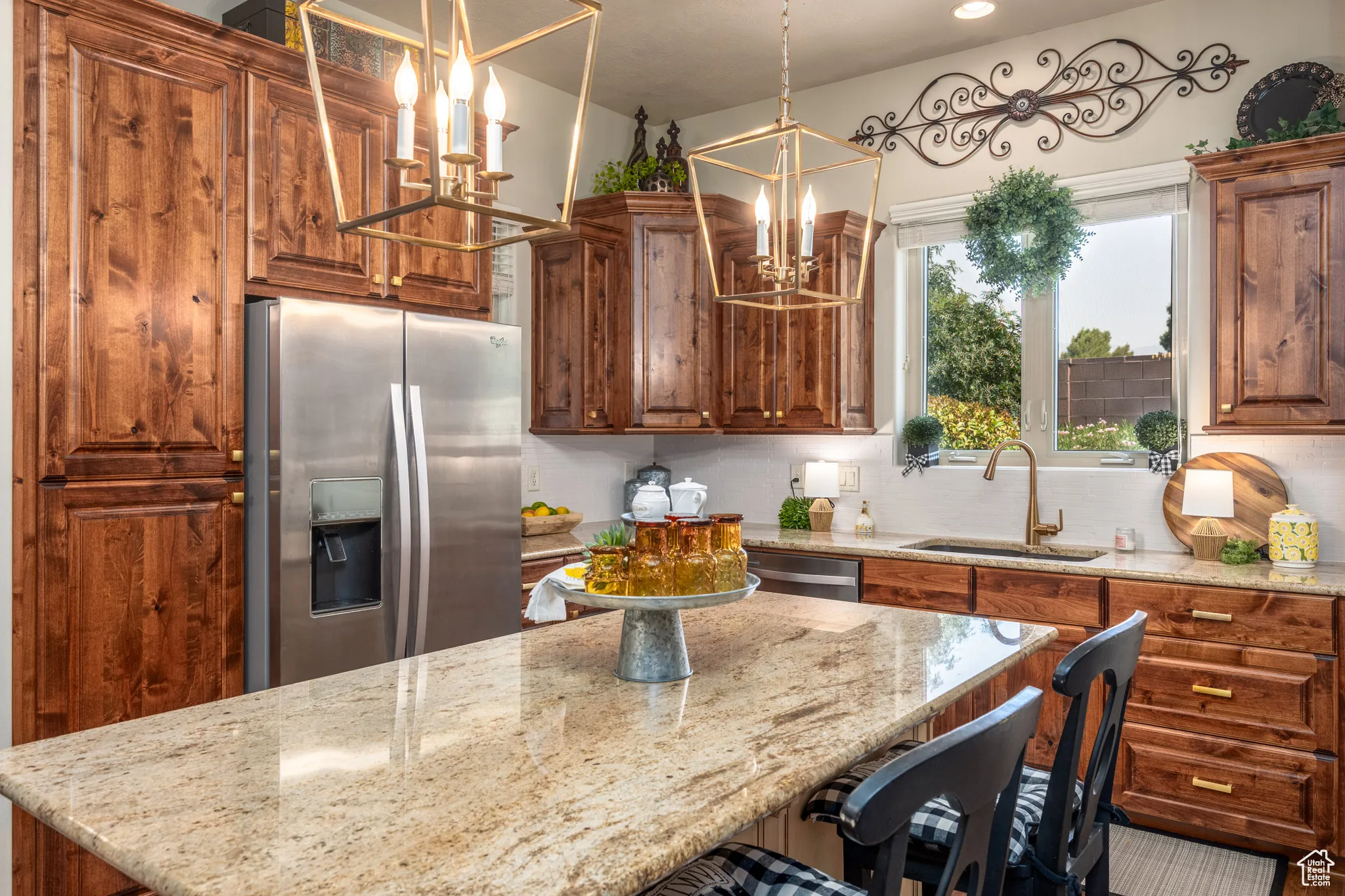 Kitchen with appliances with stainless steel finishes, tasteful backsplash, sink, light stone counters, and a notable chandelier