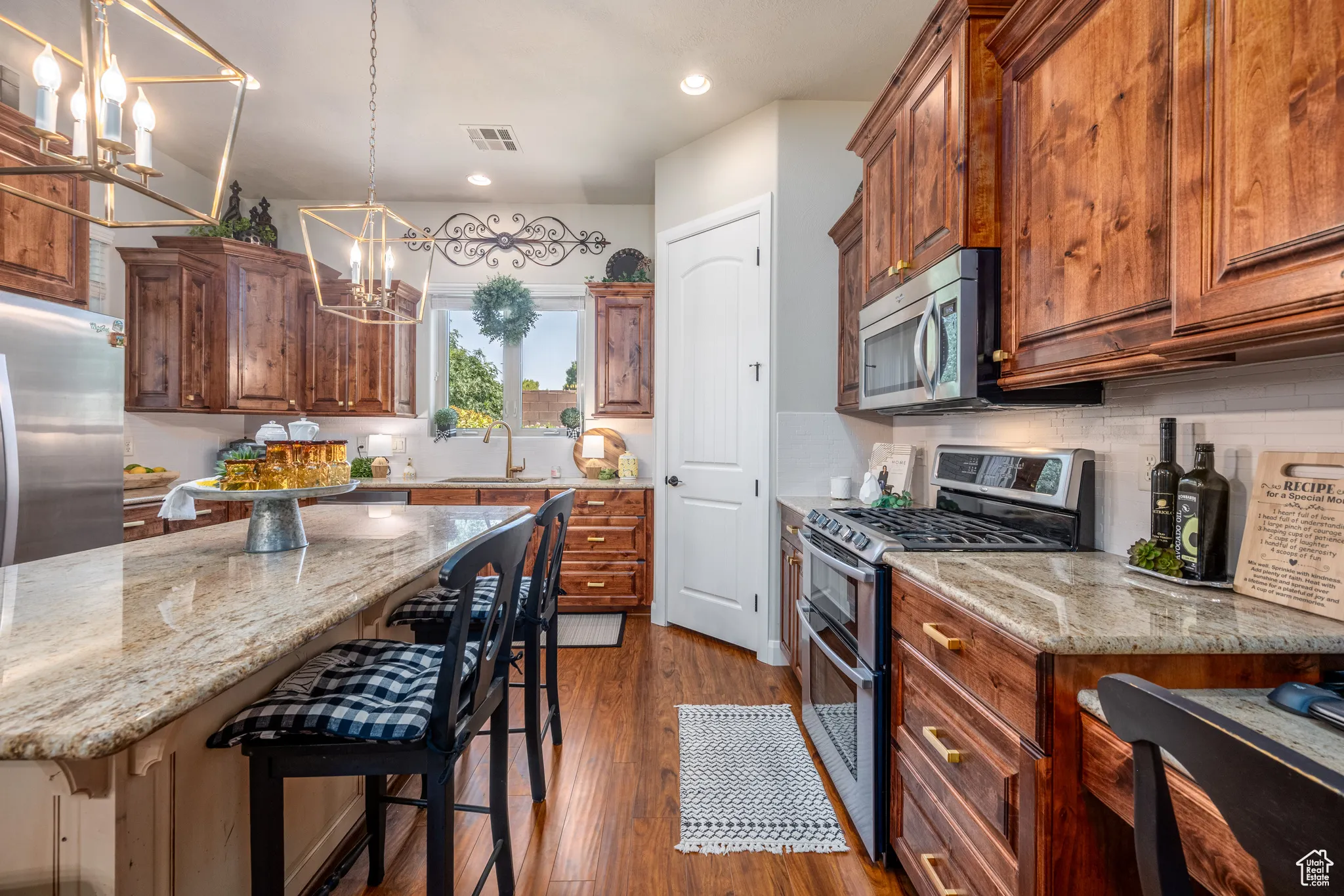 Kitchen featuring decorative light fixtures, wood-type flooring, decorative backsplash, a center island, and appliances with stainless steel finishes