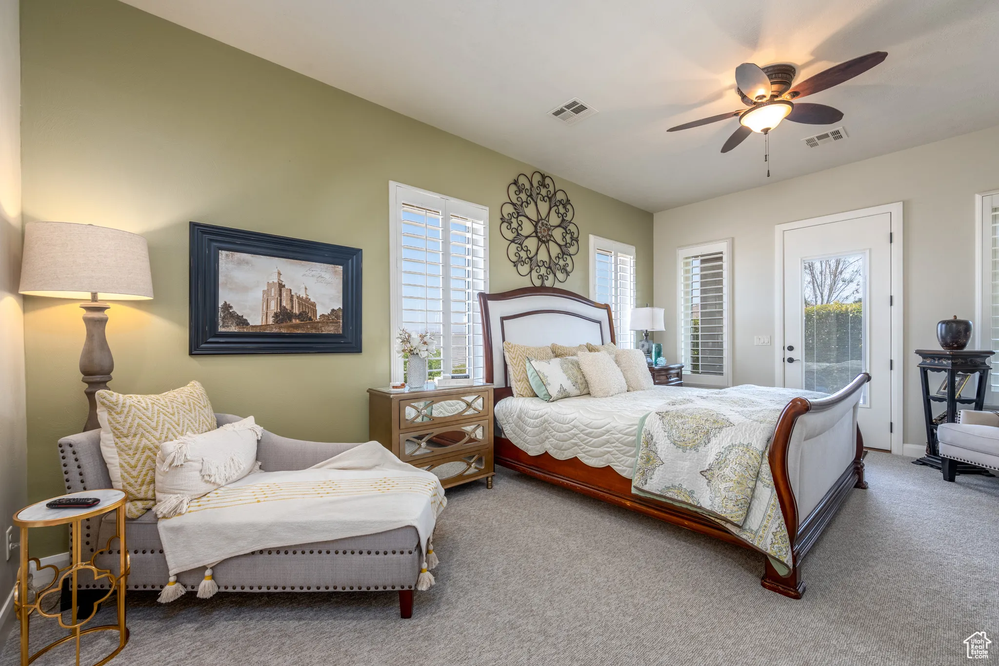 Carpeted bedroom featuring multiple windows, ceiling fan, and access to exterior