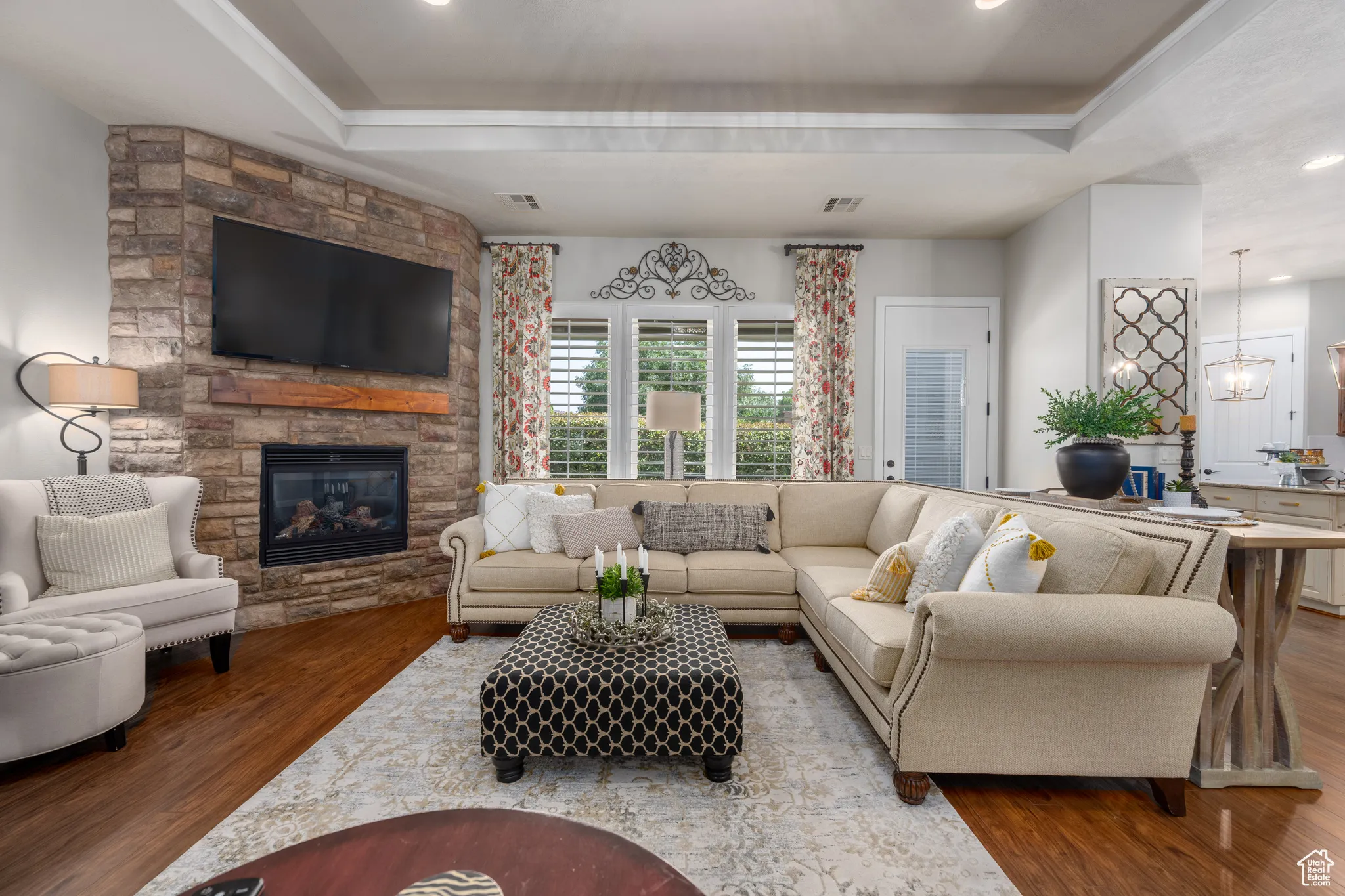 Living room with a fireplace, wood-type flooring, and a tray ceiling