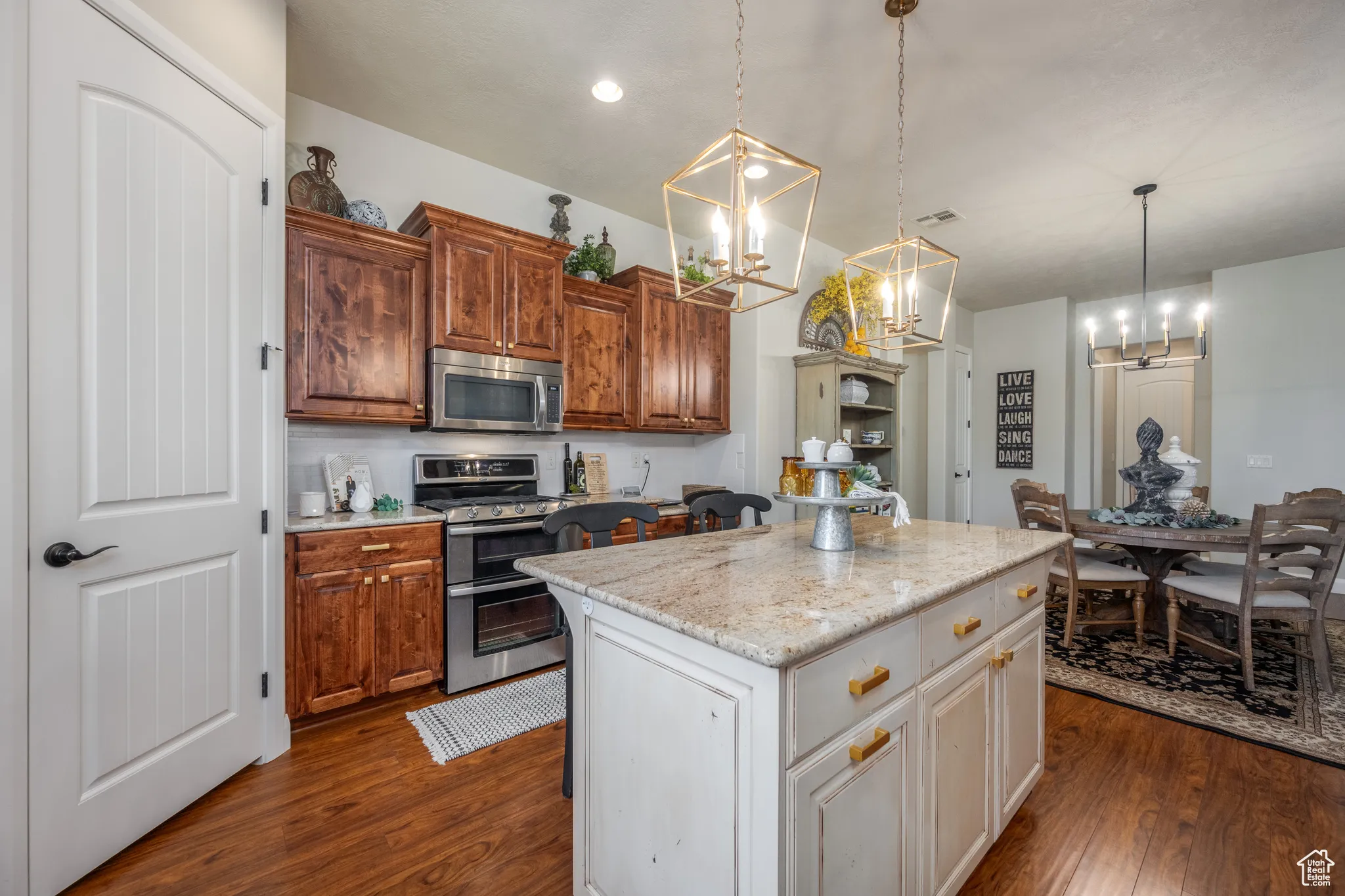 Kitchen featuring dark hardwood / wood-style flooring, white cabinets, a center island, light stone counters, and appliances with stainless steel finishes