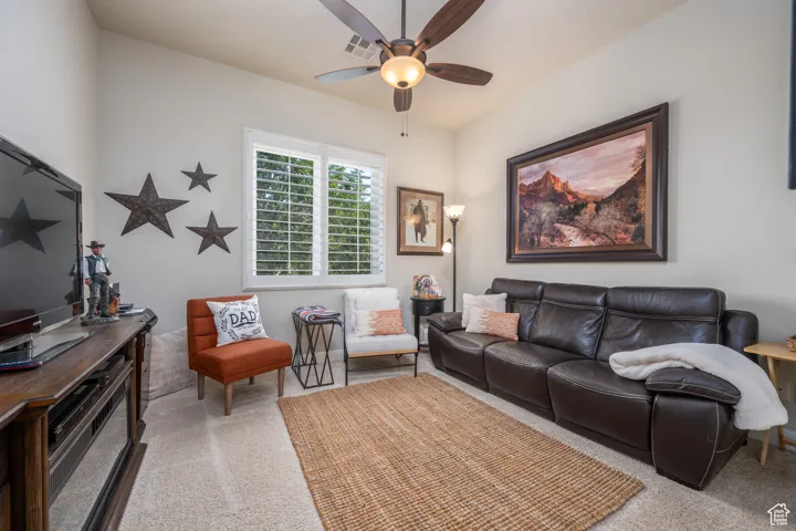 Carpeted living room featuring ceiling fan