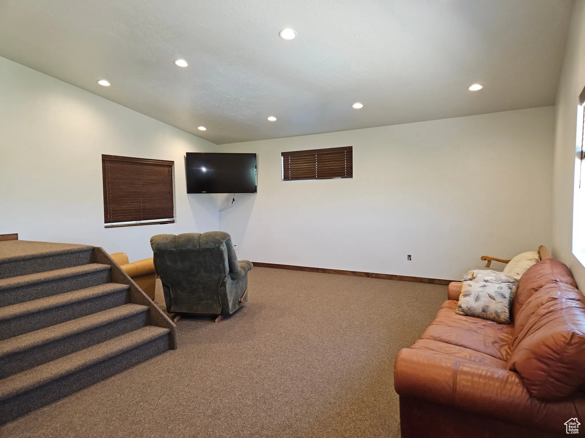 Living room with recessed lighting, carpet floors, lofted ceiling, baseboards, and stairway