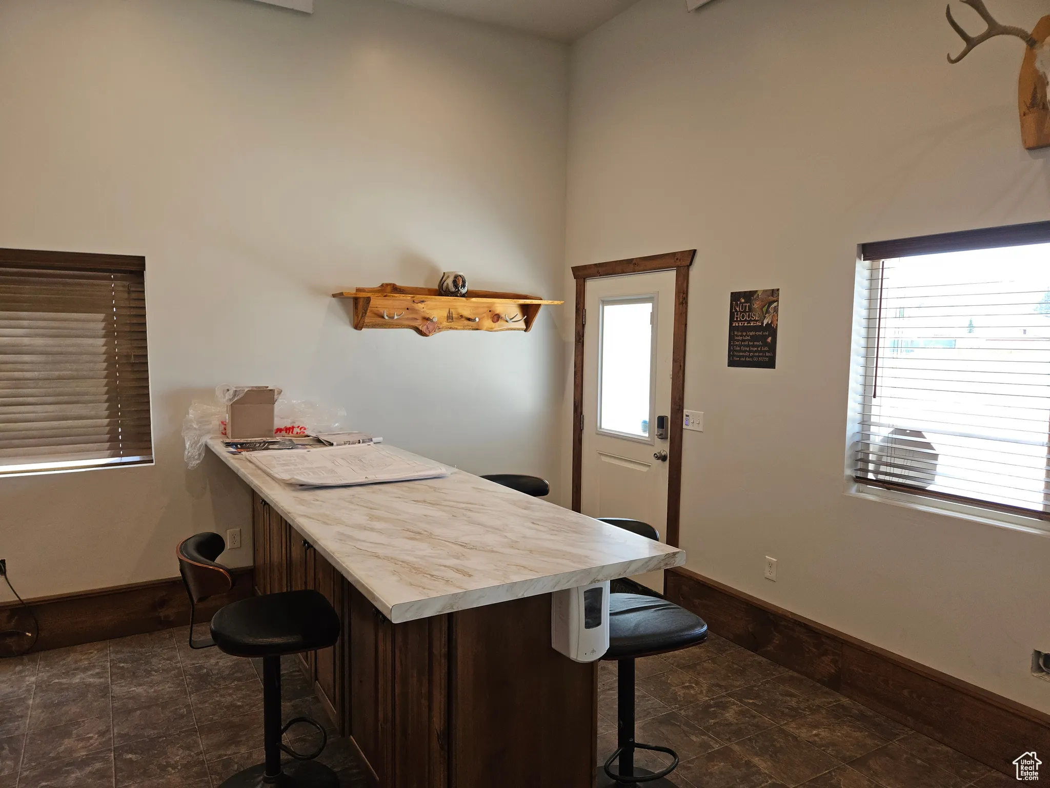 Bar area featuring stone finish floors, baseboards, and a towering ceiling