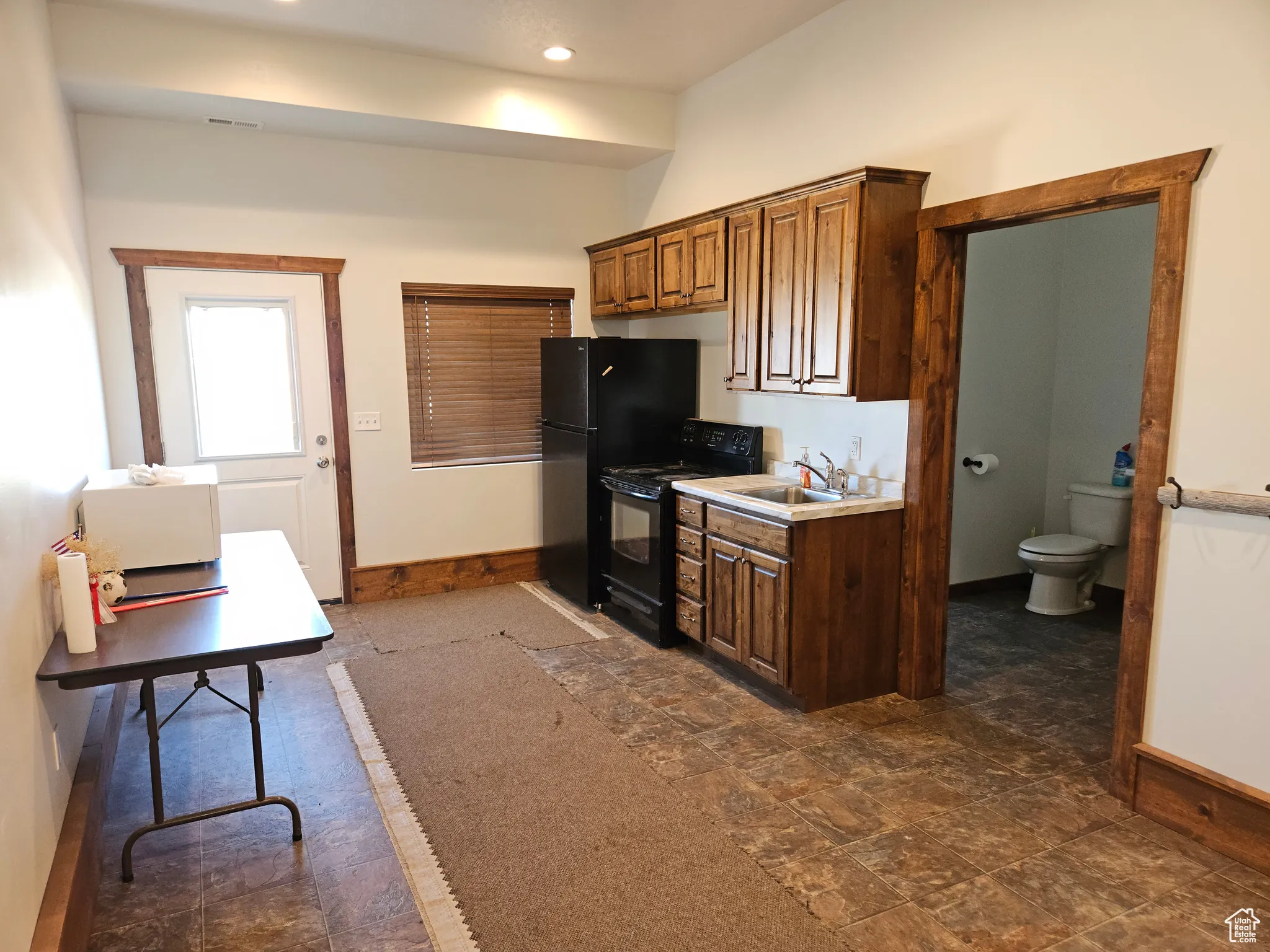 Kitchen featuring black appliances, baseboards, a sink, recessed lighting, and light countertops