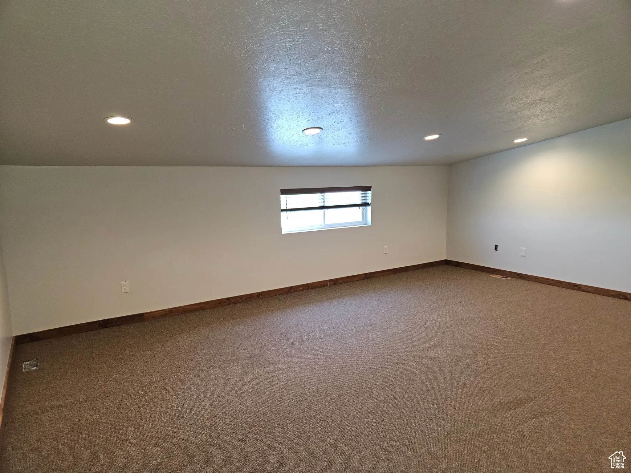 Unfurnished room with dark colored carpet, recessed lighting, baseboards, and a textured ceiling
