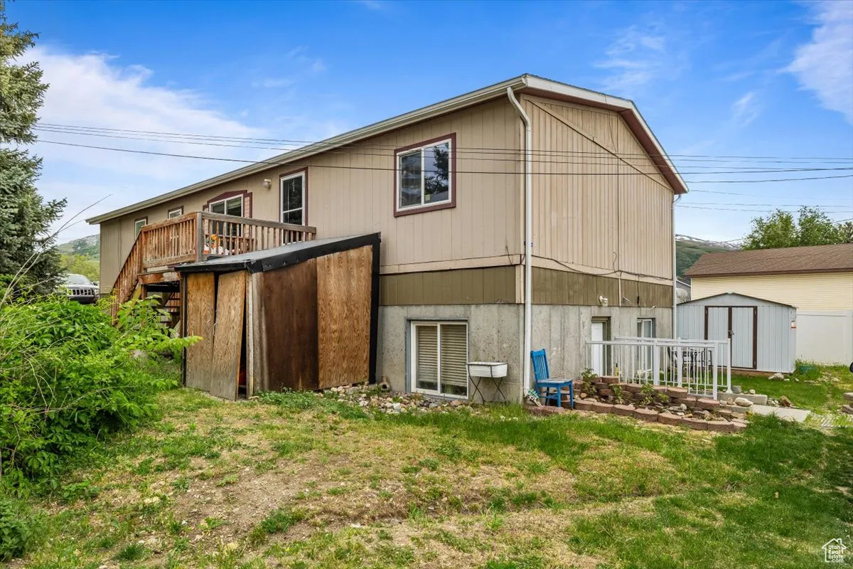 Back of property featuring a yard, a shed, and a wooden deck