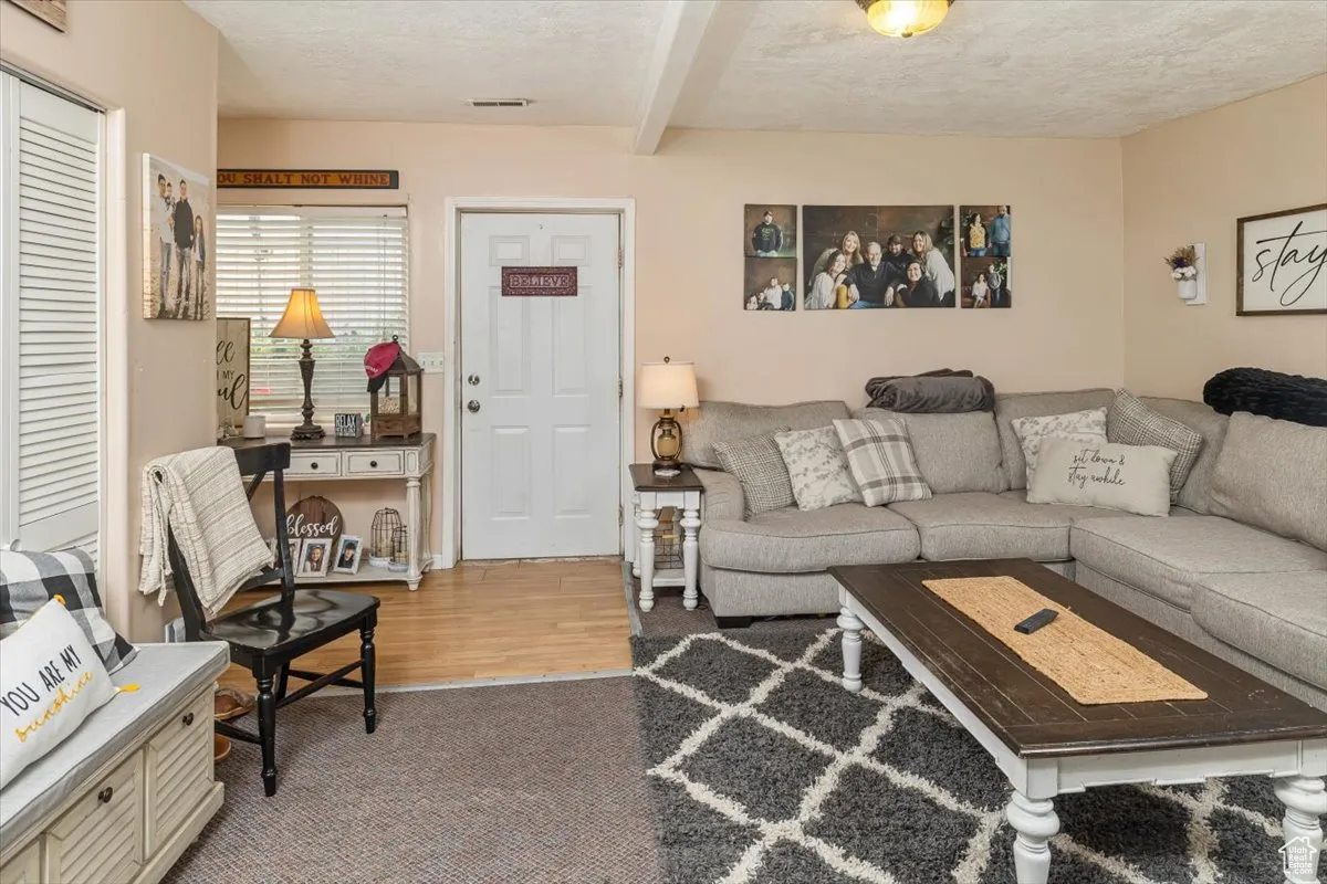 Living room (Basement)  featuring beamed ceiling, a textured ceiling, and light colored carpet
