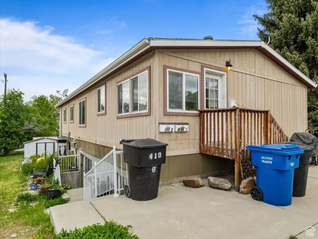 View of property exterior featuring a shed, a patio, and a deck