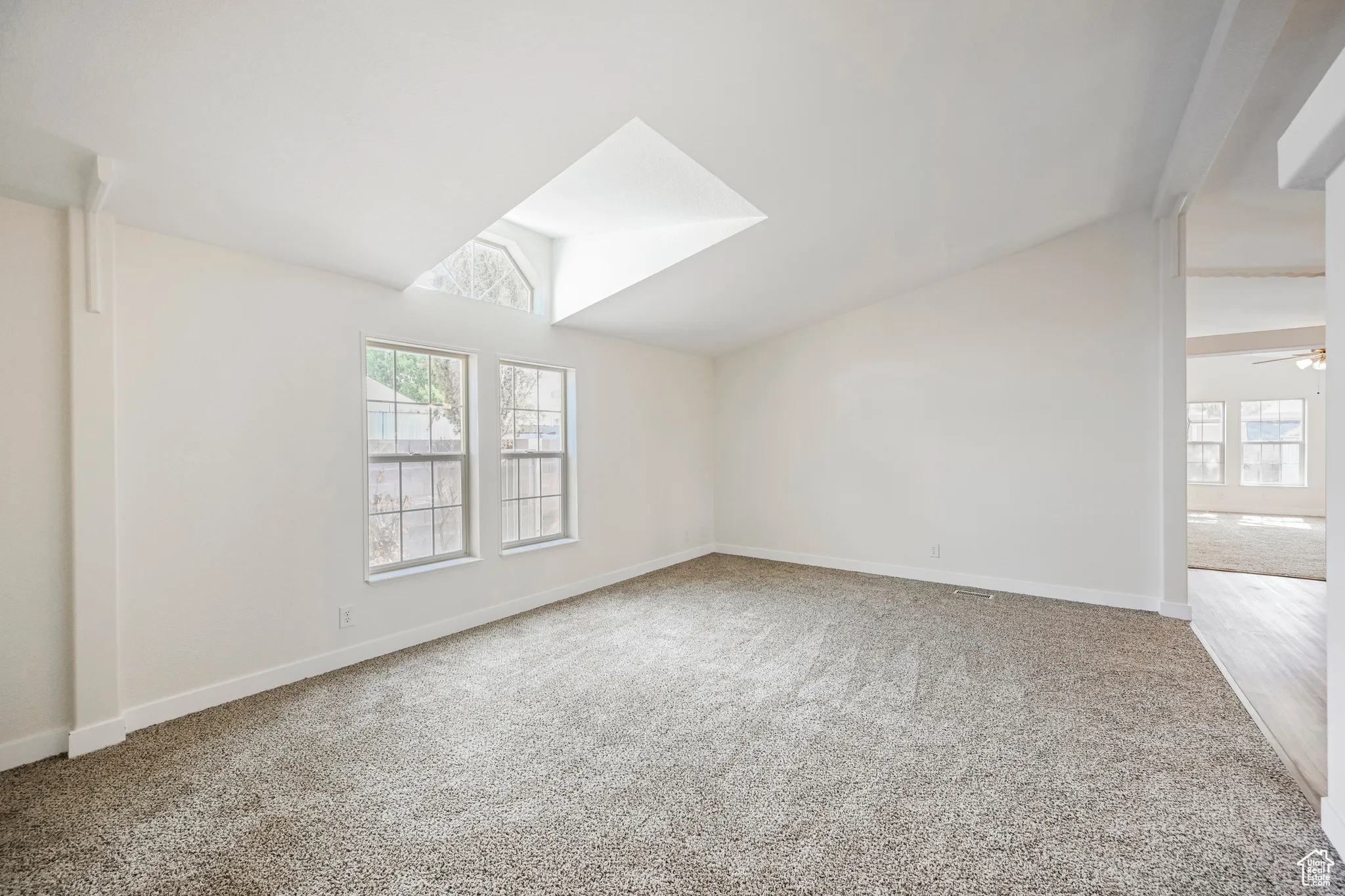 Carpeted empty room with ceiling fan and vaulted ceiling