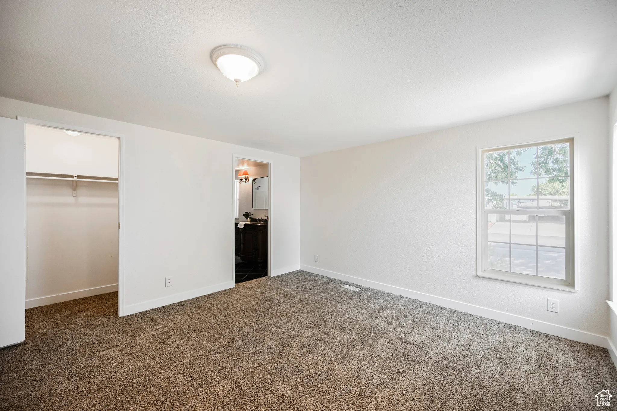 Unfurnished bedroom with a spacious closet, carpet flooring, and a closet