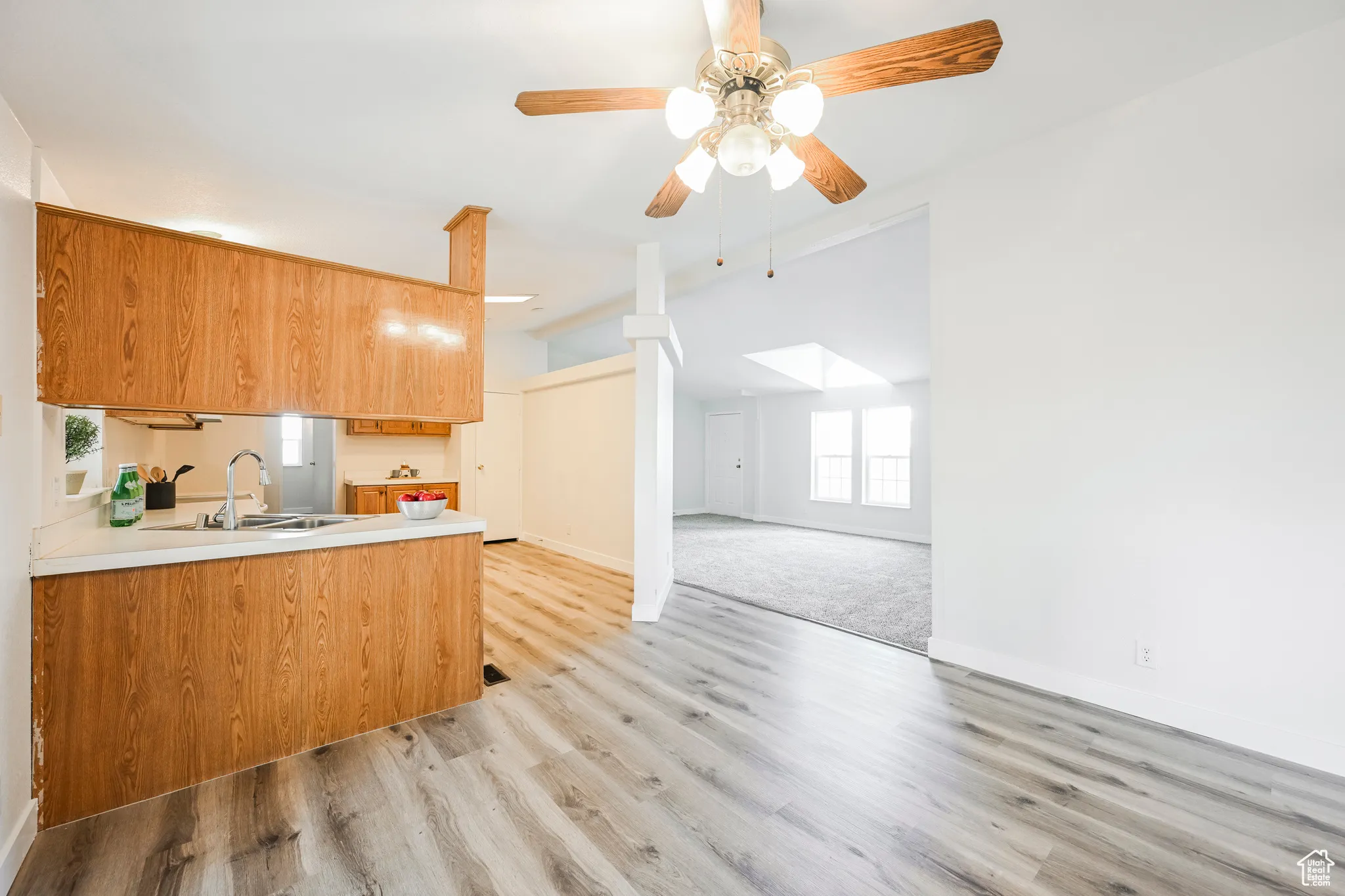 Kitchen featuring ceiling fan, sink, light colored carpet, and kitchen peninsula