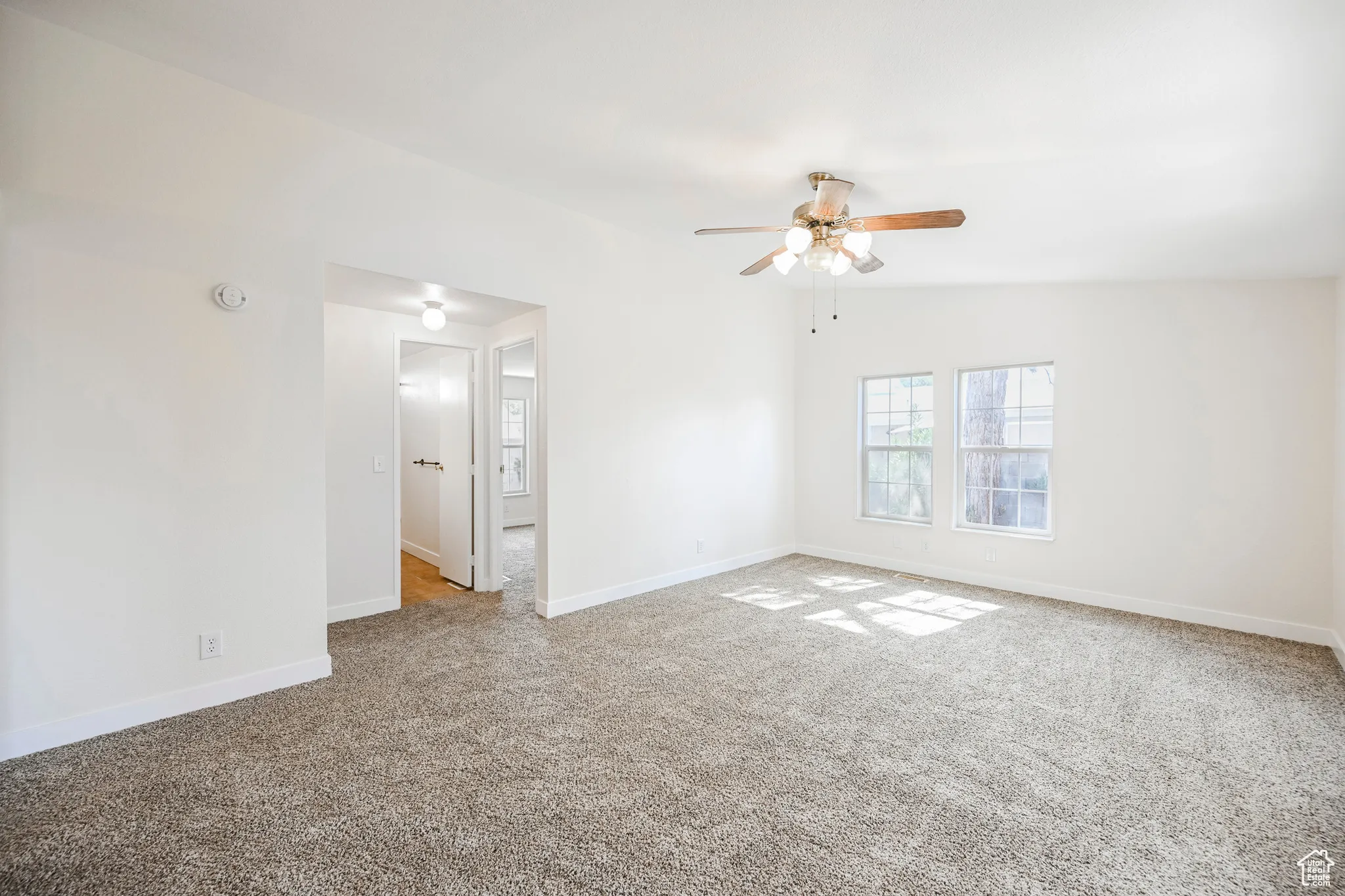 Empty room featuring lofted ceiling, light colored carpet, and ceiling fan