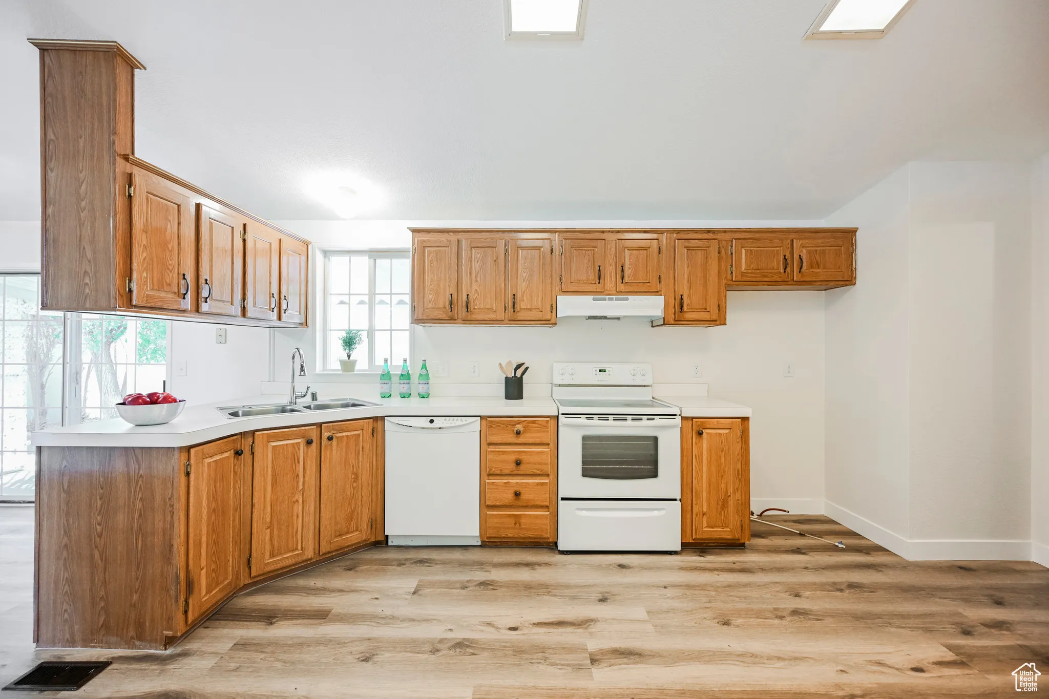 Kitchen featuring kitchen peninsula, sink, white appliances, and light hardwood / wood-style floors