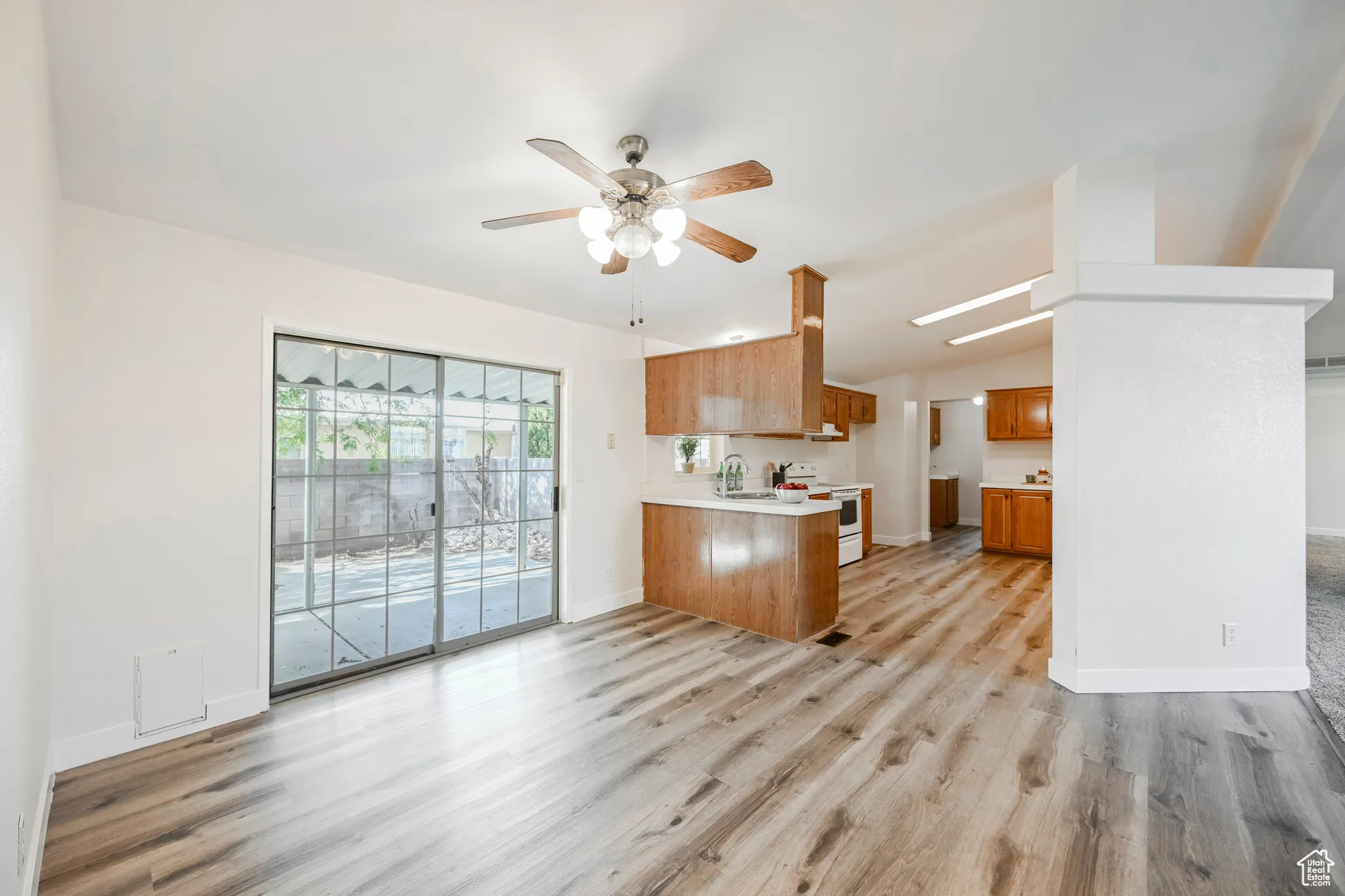 Kitchen with ceiling fan, light hardwood / wood-style flooring, kitchen peninsula, and white range oven