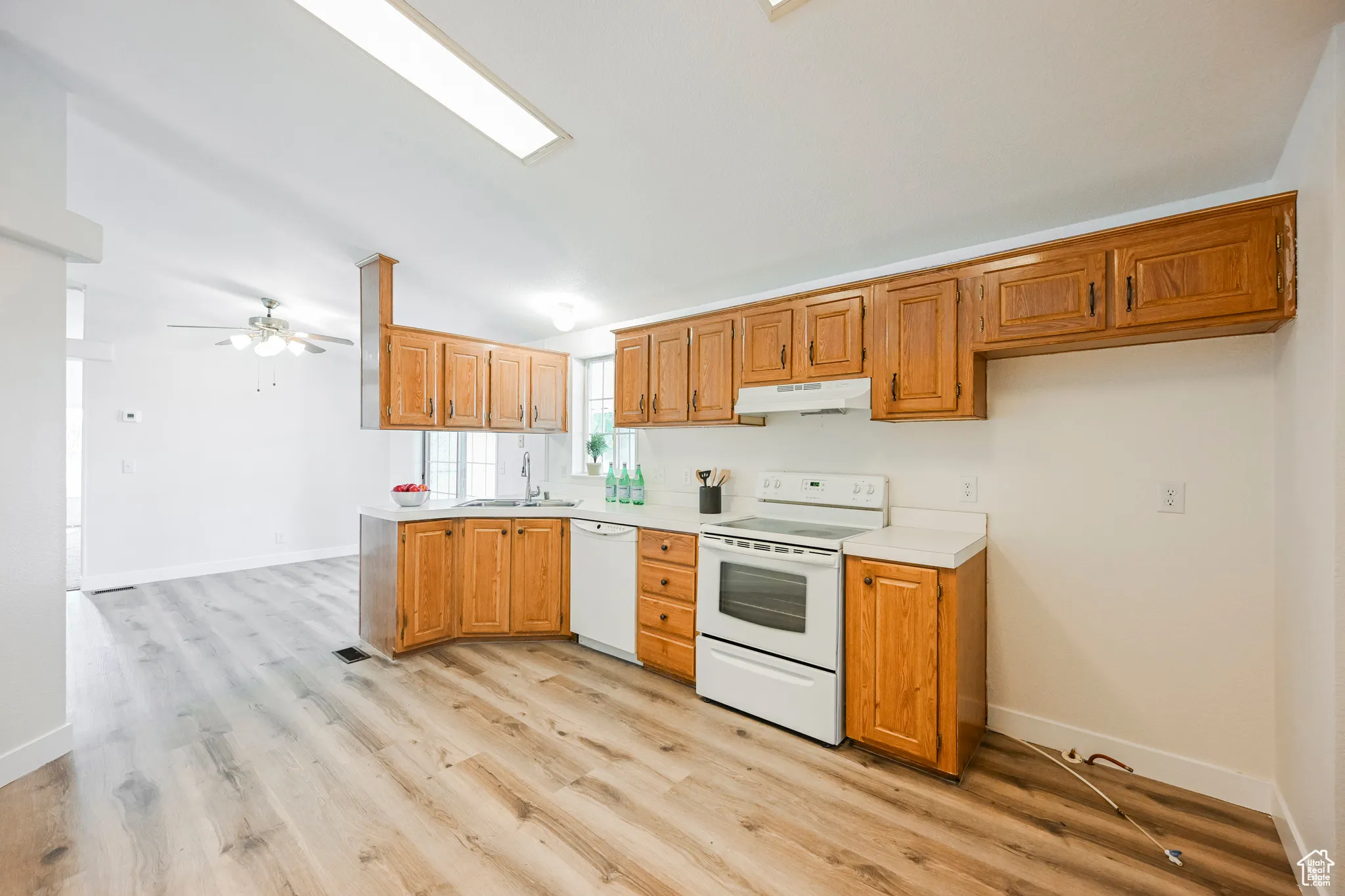 Kitchen with light hardwood / wood-style flooring, ceiling fan, vaulted ceiling, white appliances, and sink