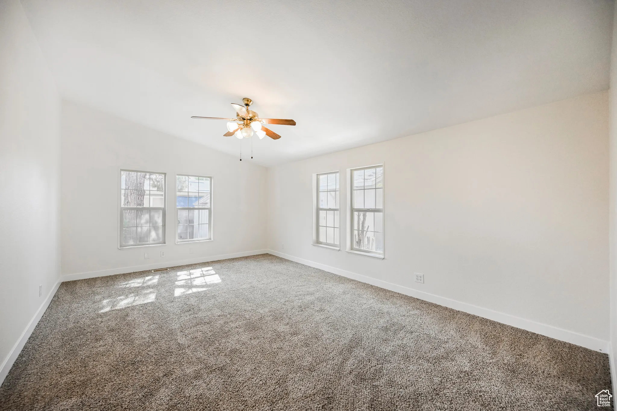 Empty room featuring ceiling fan, carpet, and lofted ceiling