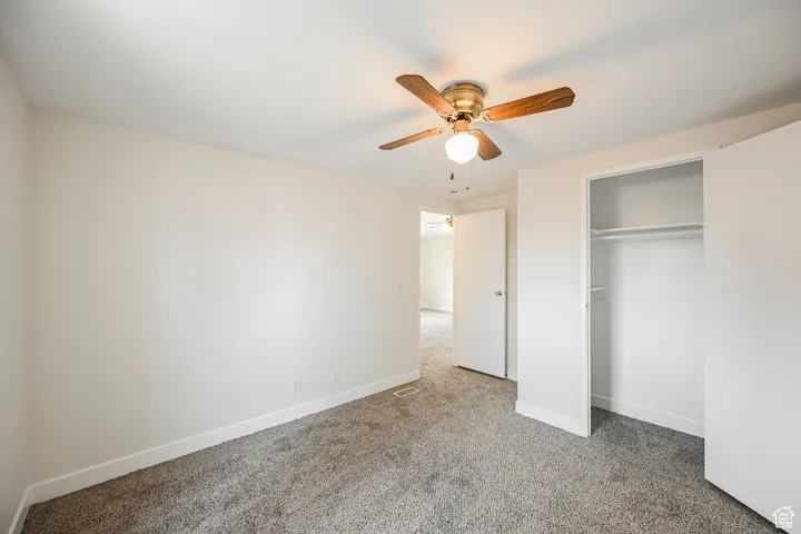 Unfurnished bedroom with ceiling fan, carpet flooring, and a closet
