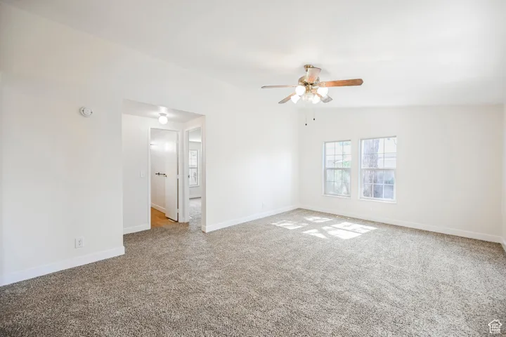 Empty room featuring lofted ceiling, light colored carpet, and ceiling fan
