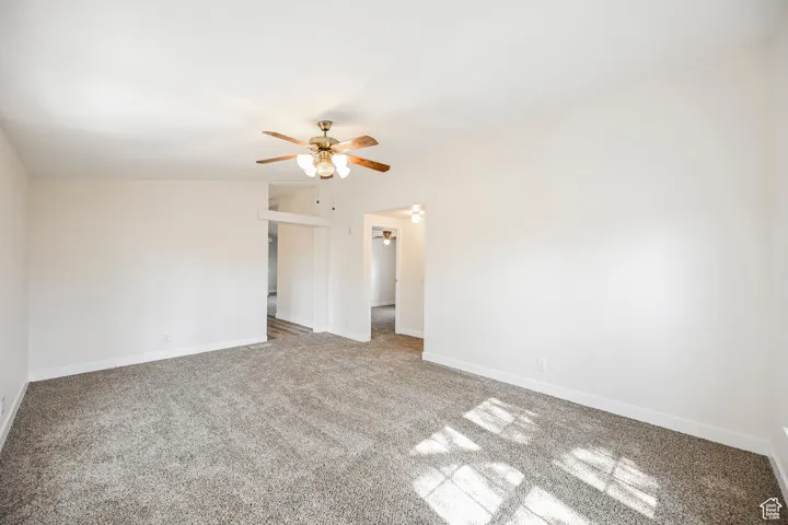 Unfurnished room featuring lofted ceiling, carpet flooring, and ceiling fan
